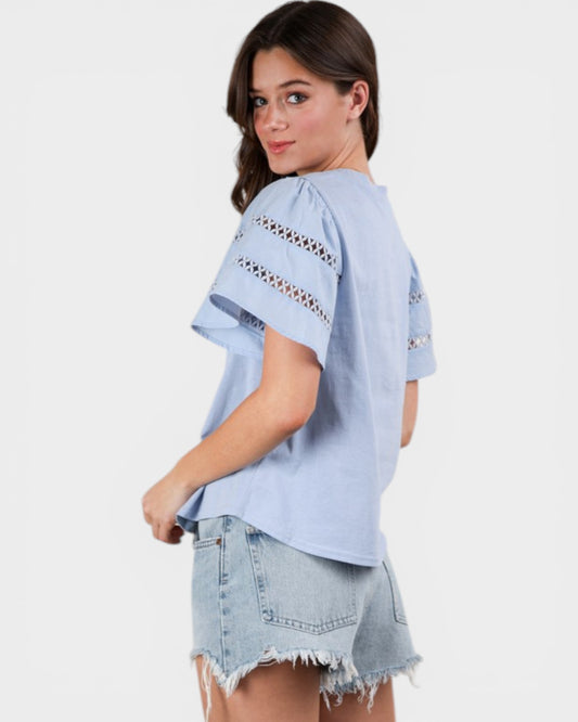 Woman wearing a light blue blouse with lace details on a white background