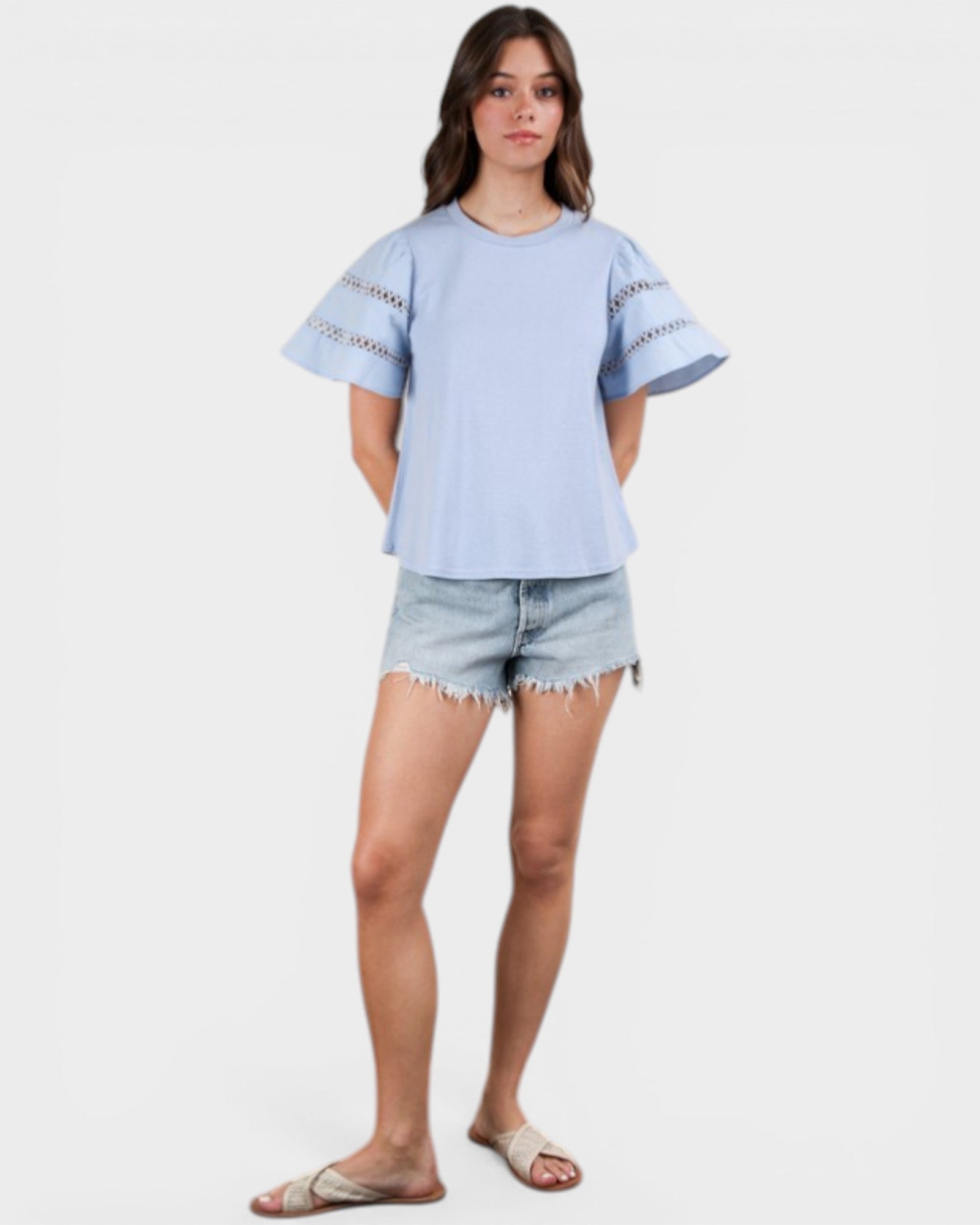 Woman wearing a light blue t-shirt and denim shorts on a white background