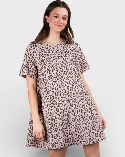 Woman wearing a leopard print dress on a plain background