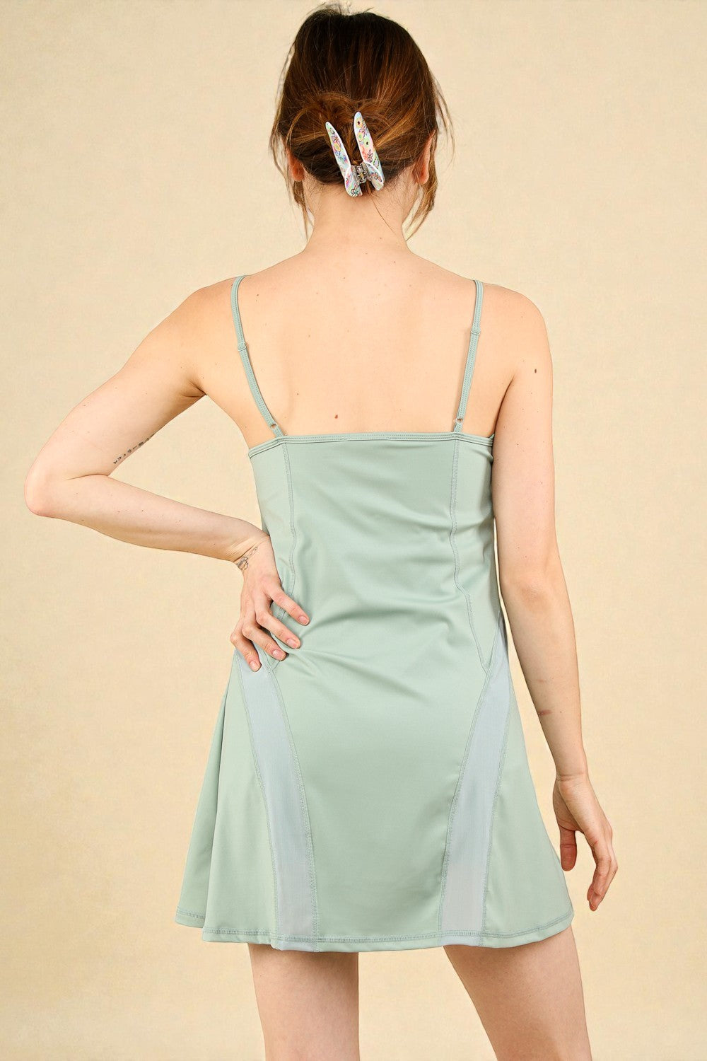Person wearing a light green slip dress against a beige background