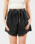 Person wearing black denim shorts with a drawstring on a white background