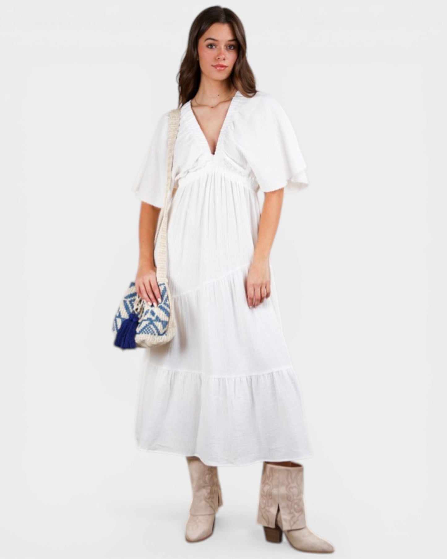 Woman wearing a white dress holding a patterned bag on a white background