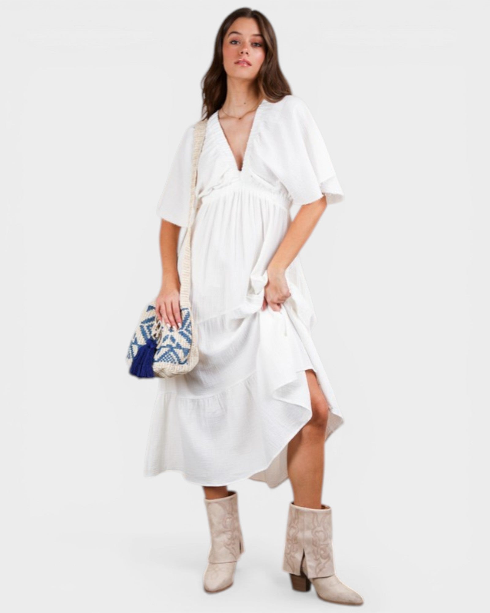 Woman wearing a white dress with a blue and white patterned clutch on a white background