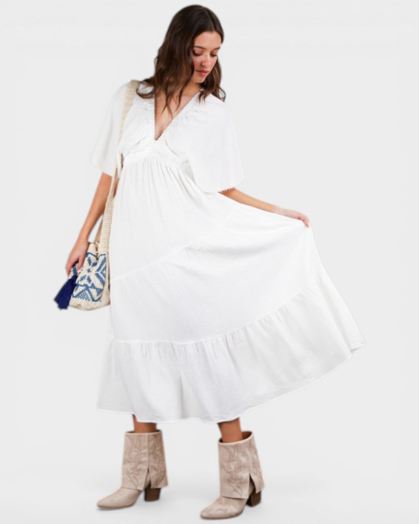 Woman wearing a white dress with a blue and white patterned bag on a white background