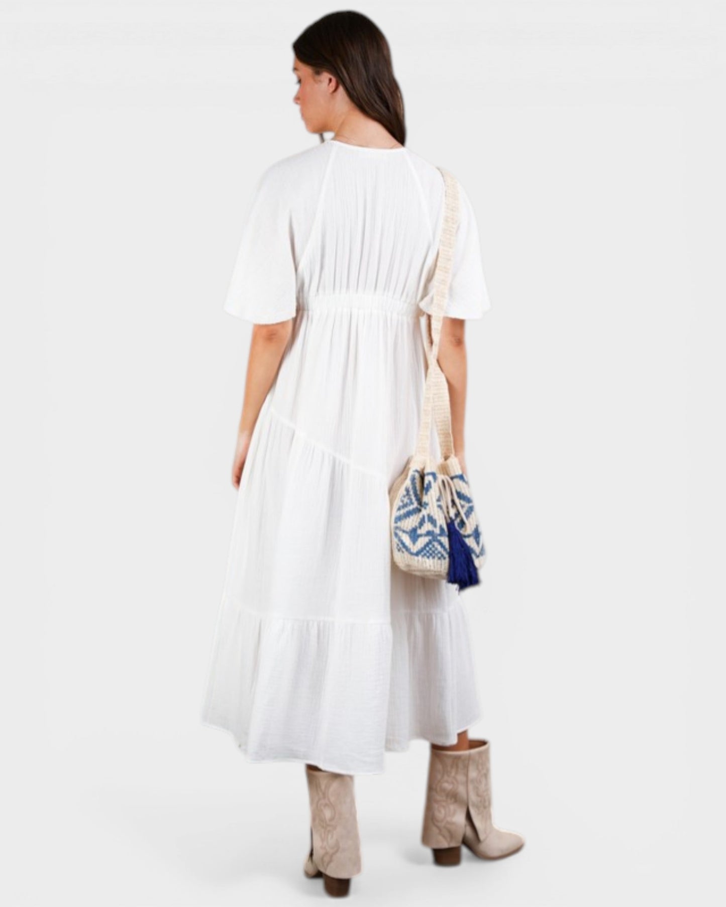 Woman wearing a white dress holding a patterned bag on a white background