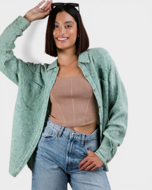 Woman wearing a green jacket, beige top, and blue jeans on a white background