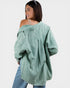 Woman wearing a green oversized jacket and blue jeans on a white background