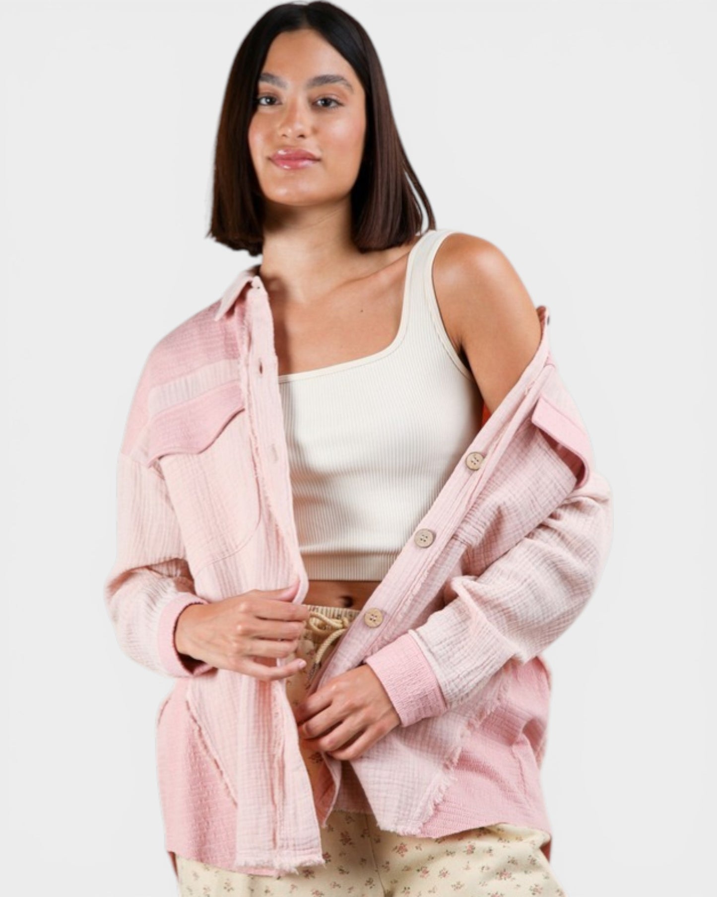 Woman wearing a pink denim jacket over a white top on a white background