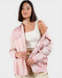 Woman wearing a pink denim jacket over a white top on a white background