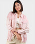 Woman wearing a light pink denim jacket on a white background