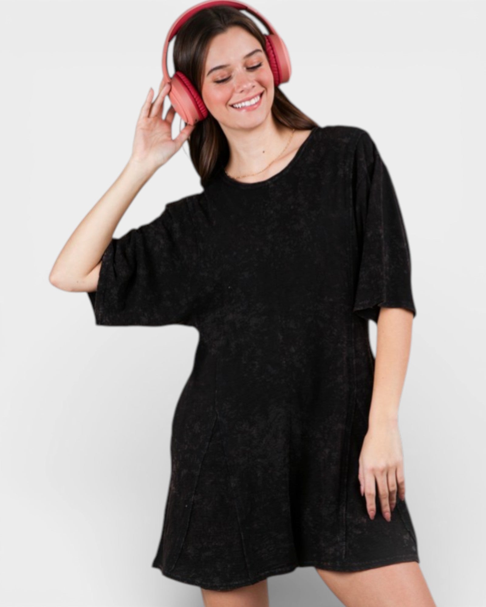 Woman wearing a black dress and pink headphones on a white background