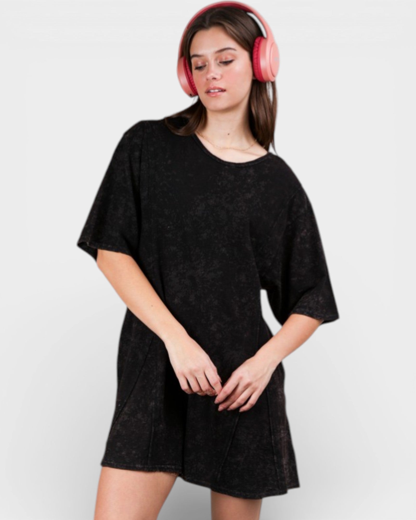 Woman wearing a black dress and pink headphones on a white background