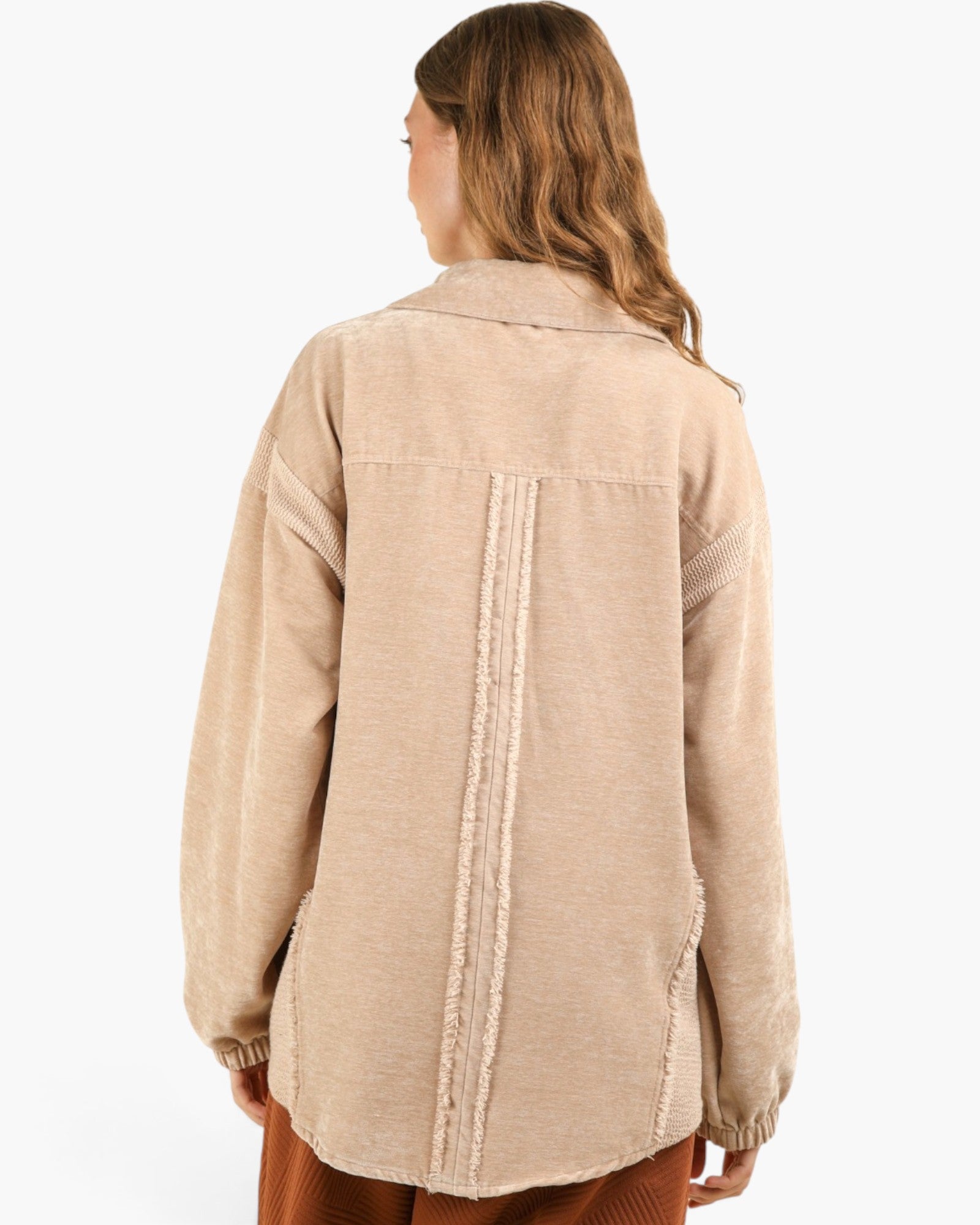 A woman shown from the back wearing a beige textured long-sleeve shirt jacket with a vertical seam detail on the back, set against a plain white background.