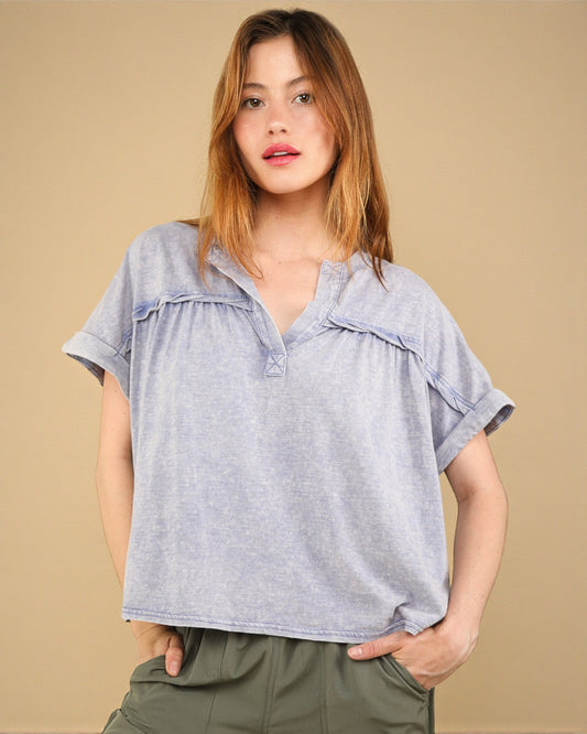 Woman wearing a light blue blouse with ruffled details on a beige background