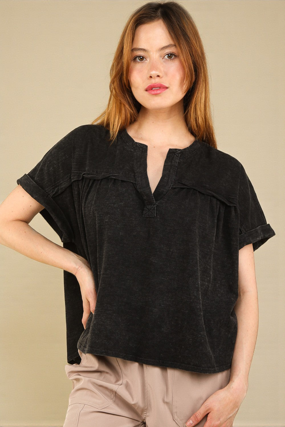 Woman wearing a black top with a beige background