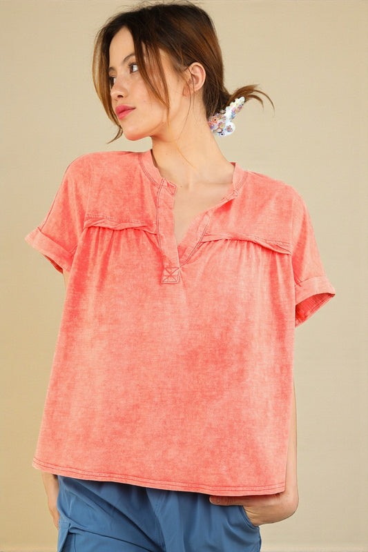 Woman wearing a coral short-sleeve top against a beige background