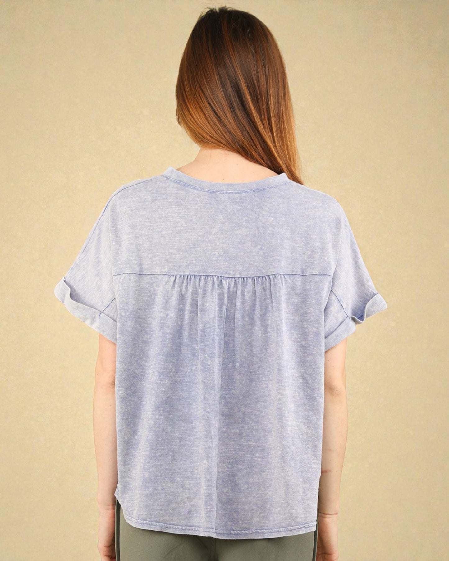 Woman wearing a light blue t-shirt against a beige background