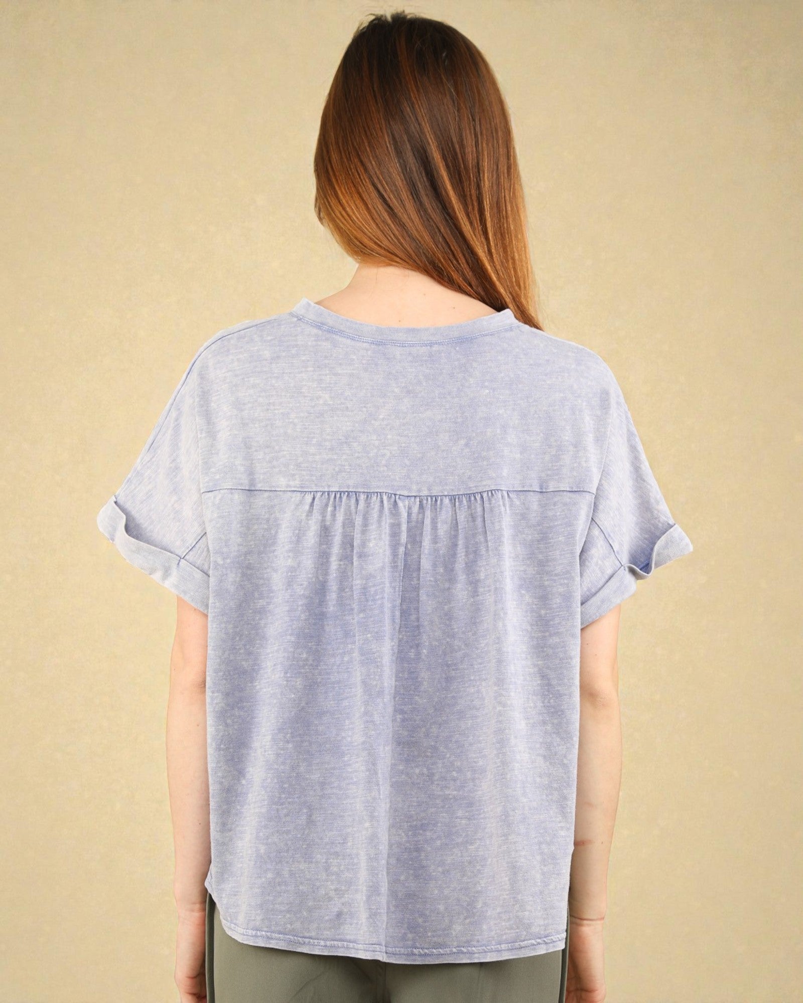 Woman wearing a light blue t-shirt against a beige background