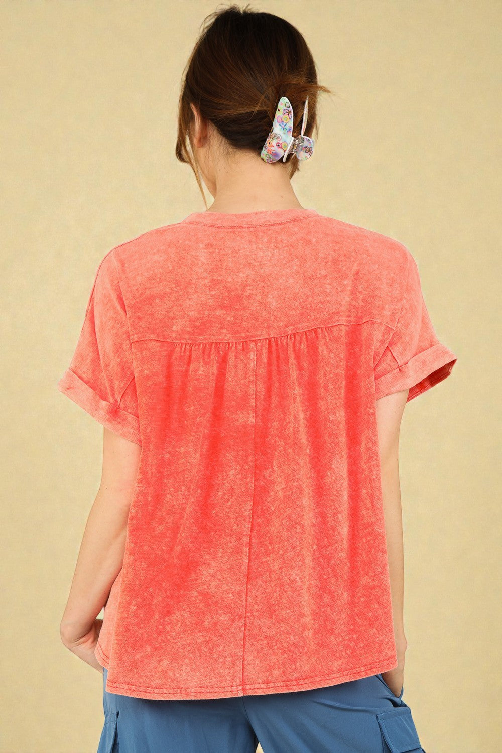 Person wearing a coral t-shirt with a beige background