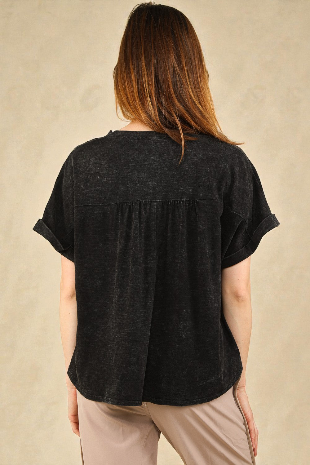 Person wearing a black short-sleeve top against a beige background