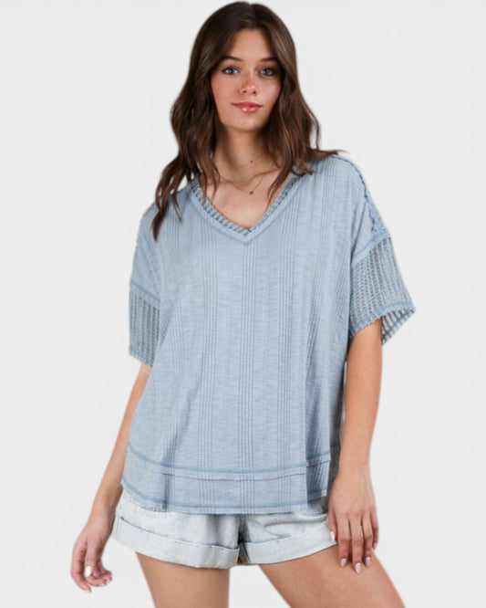 Woman wearing a light blue patterned top and shorts on a white background