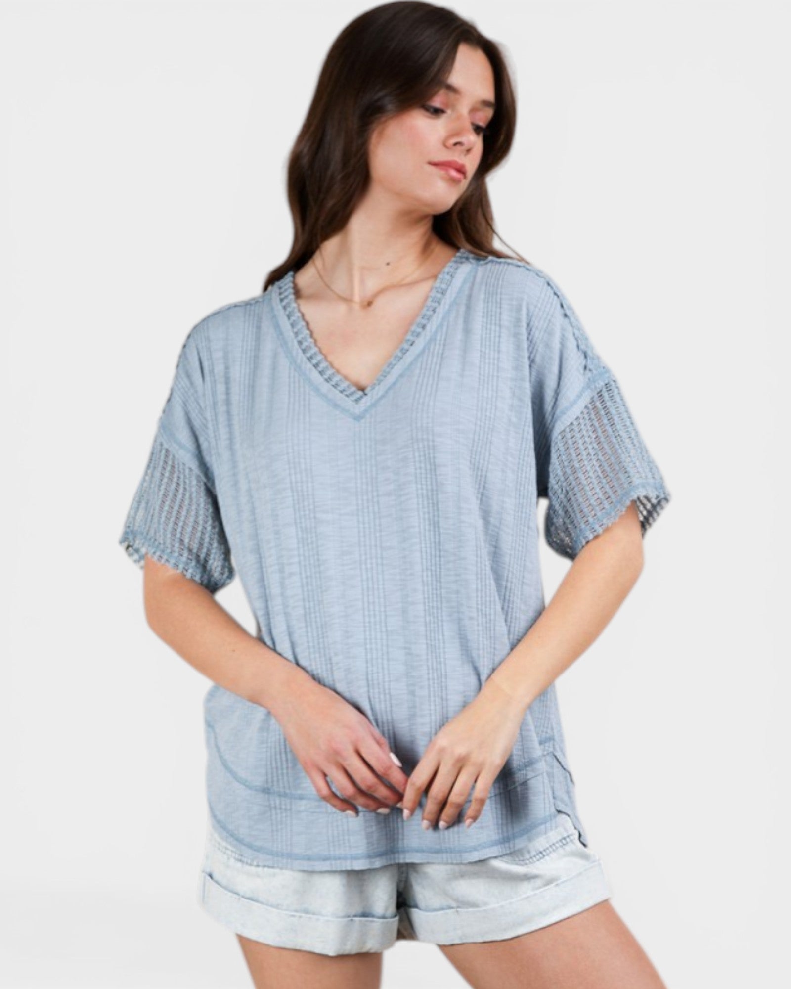 Woman wearing a blue patterned top and shorts on a white background