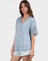 Woman wearing a light blue textured top and shorts on a white background