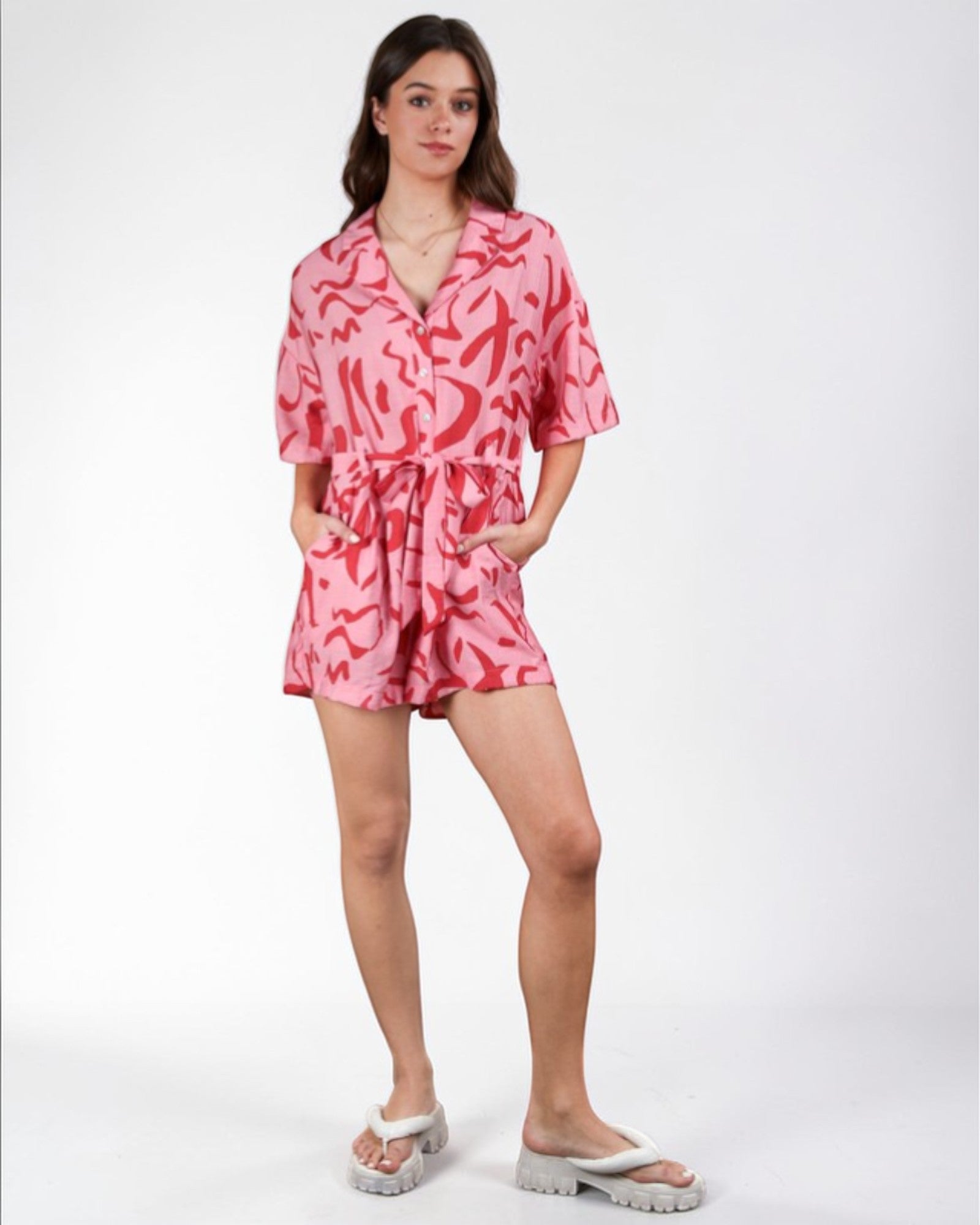 Woman wearing a pink patterned romper on a white background