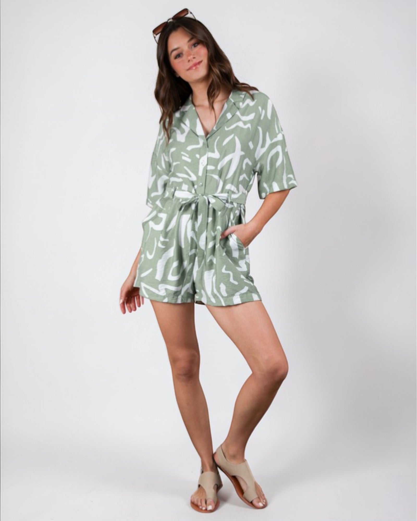 Woman wearing a green patterned romper on a white background