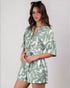 Woman wearing a green and white patterned romper against a plain background