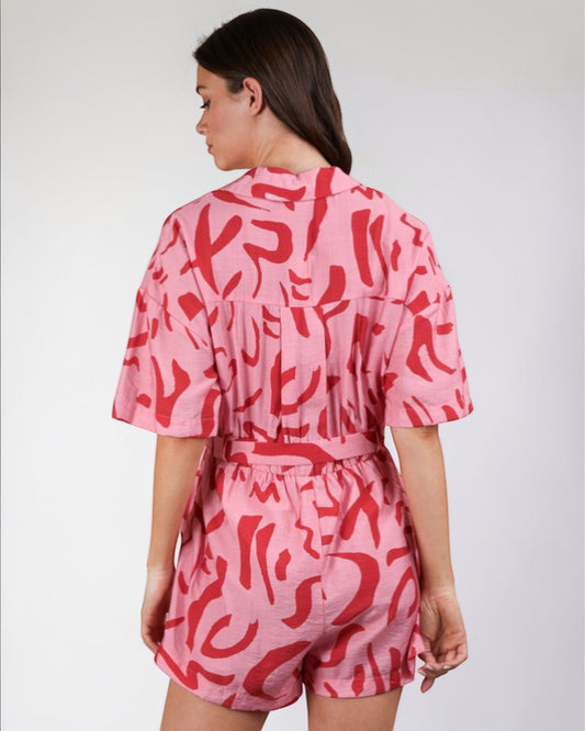 Person wearing a pink and red patterned outfit on a plain background