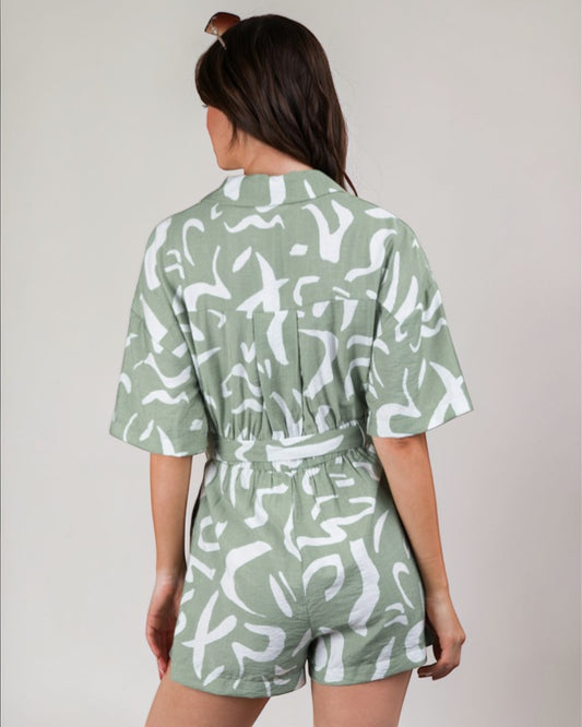 Person wearing a green and white patterned romper against a plain background