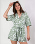 Woman wearing a green and white patterned romper against a plain background
