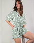 Woman wearing a green and white patterned romper against a plain background