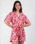 Woman wearing a pink and red patterned romper on a white background