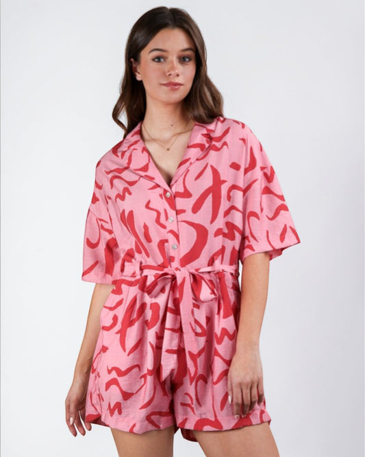 Woman wearing a pink romper with red abstract patterns on a white background