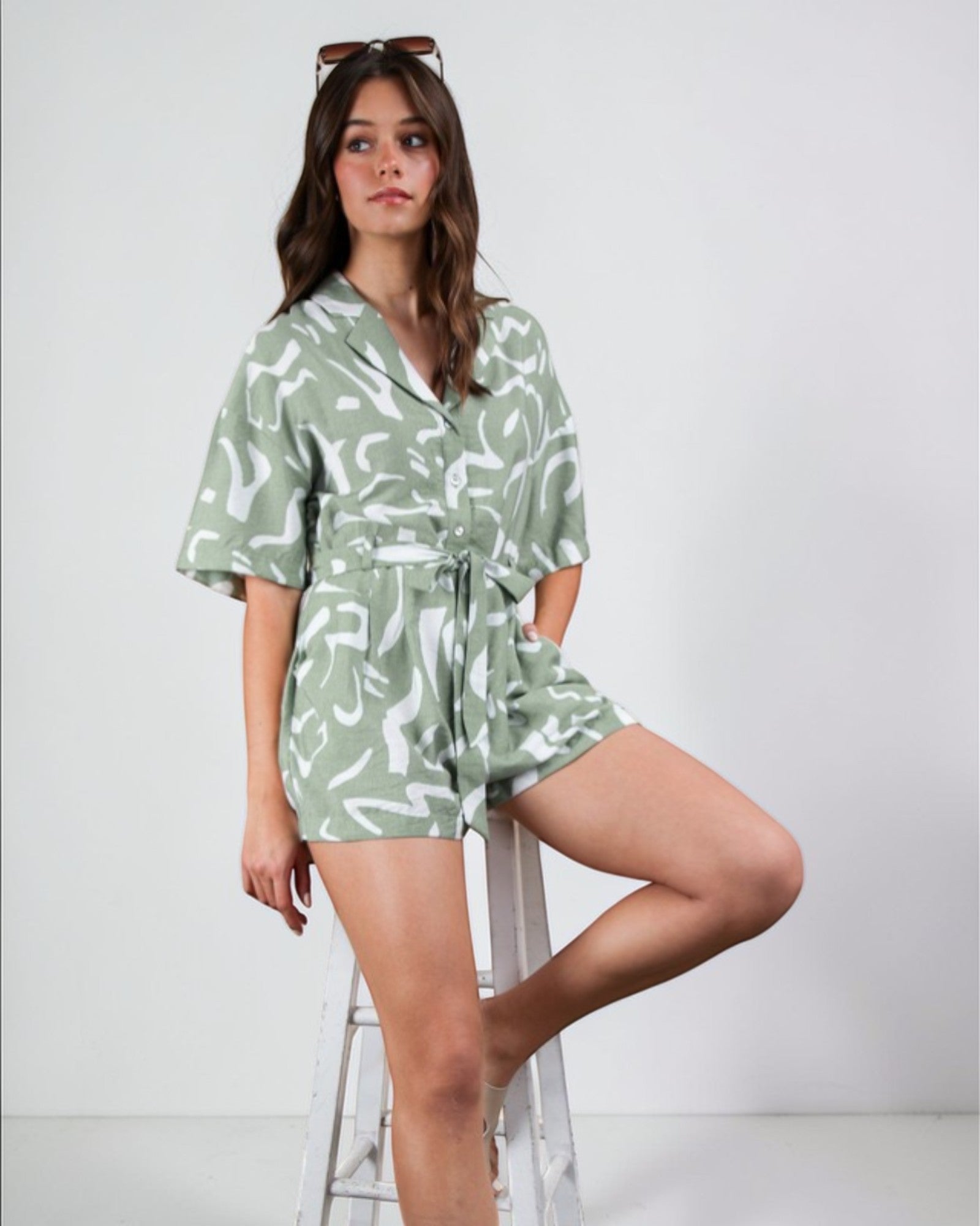 Woman wearing a green and white patterned romper on a white background