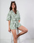 Woman wearing a green and white patterned romper on a white background