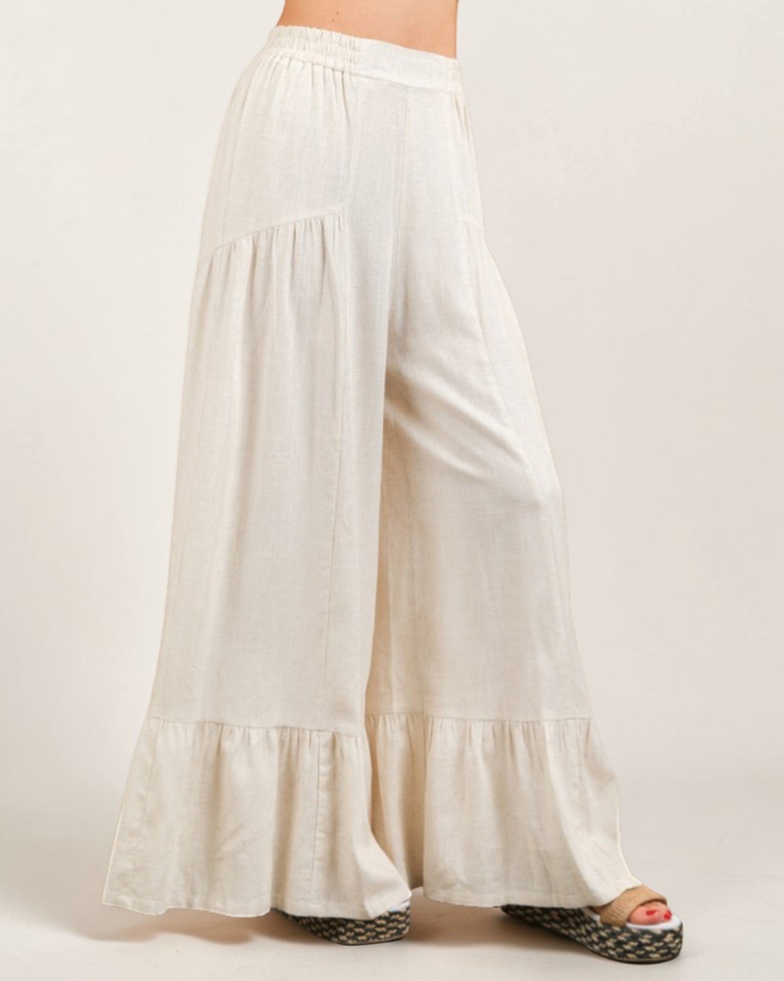 White wide-leg pants with ruffled bottom on a white background