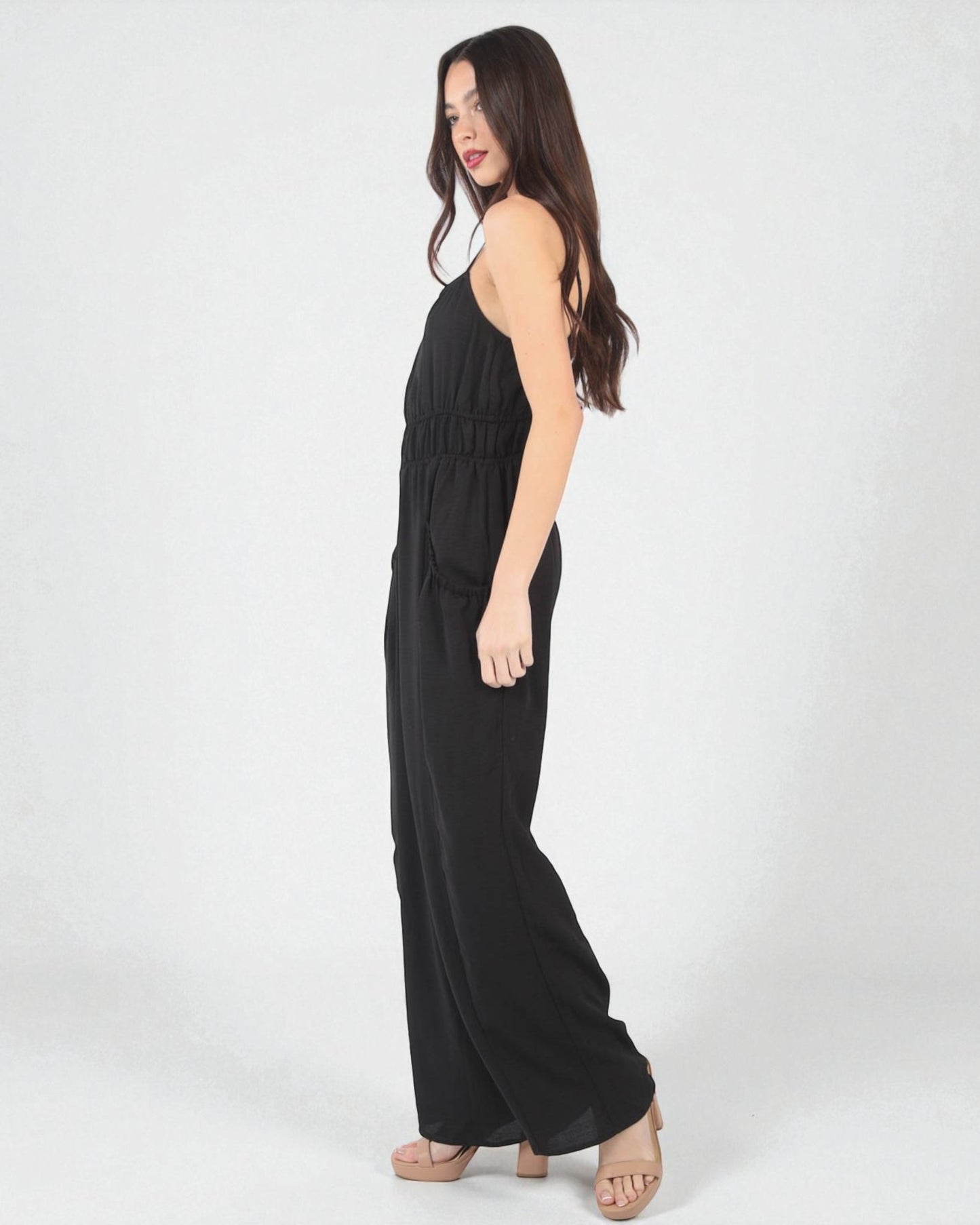 Woman wearing a black sleeveless jumpsuit on a white background