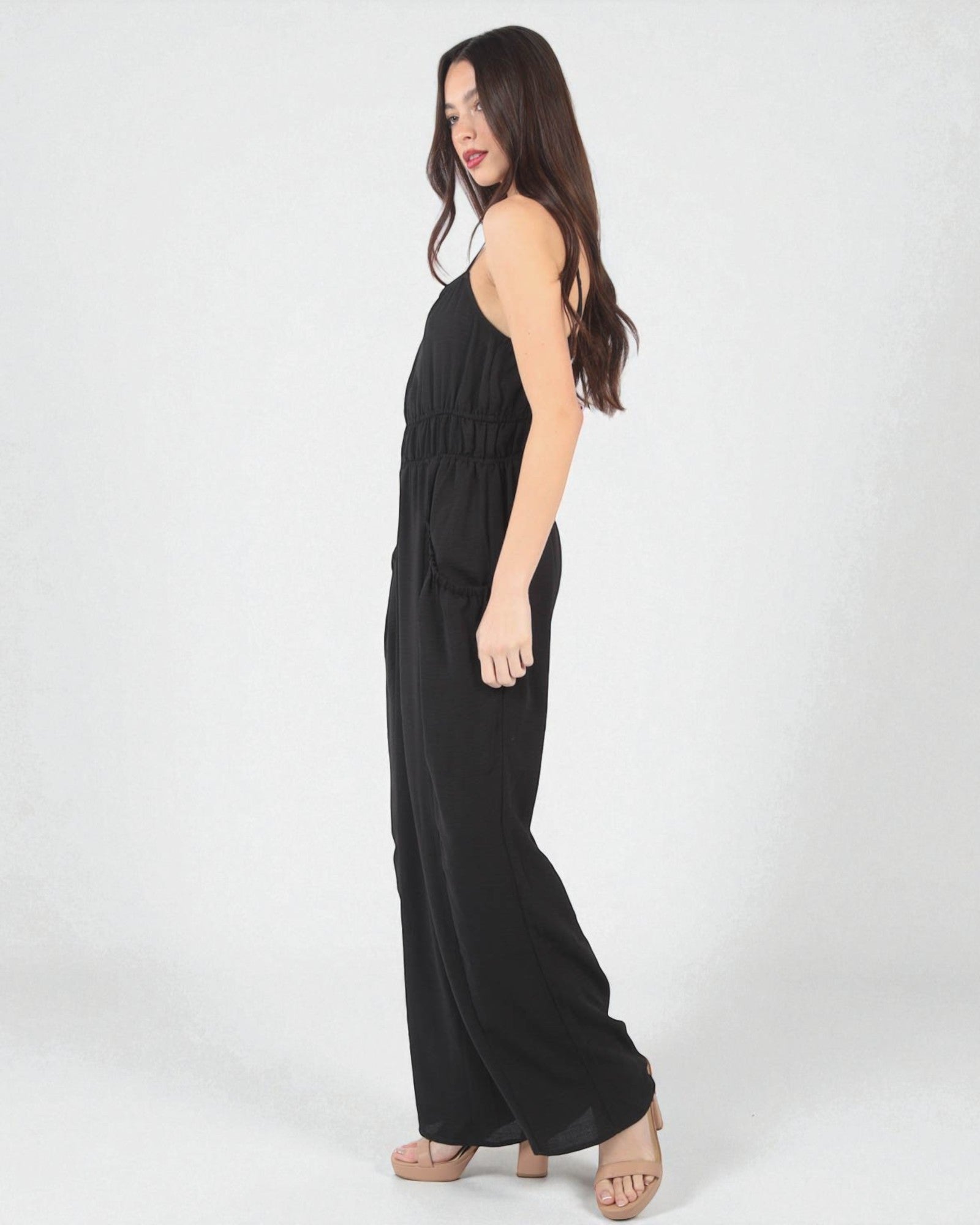 Woman wearing a black sleeveless jumpsuit on a white background