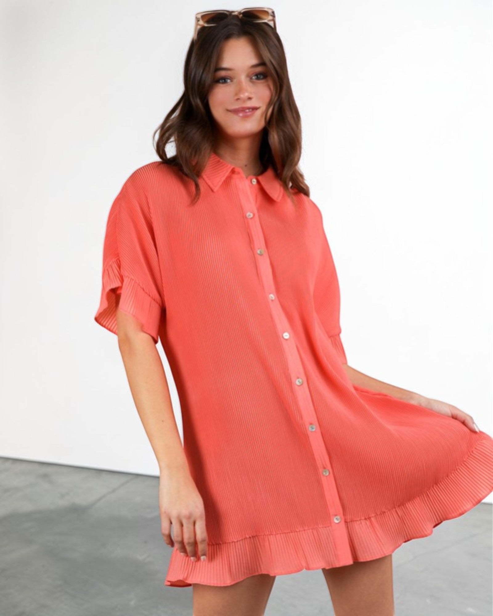 Woman wearing a coral shirt dress against a white background