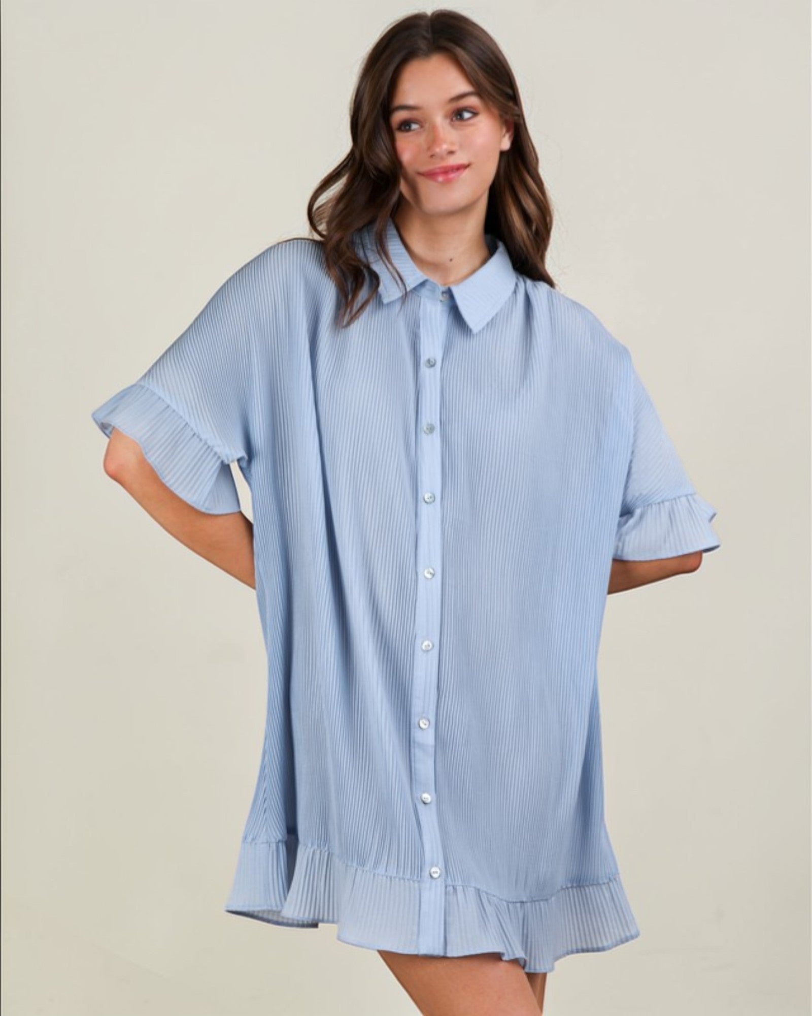 Woman wearing a light blue striped shirt against a beige background