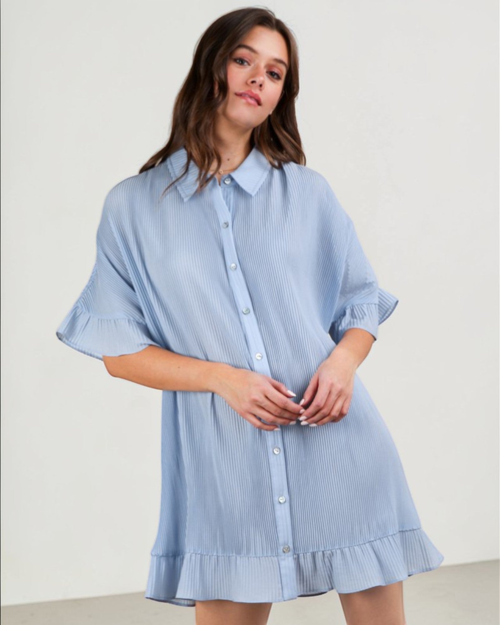 Woman wearing a light blue checkered dress against a plain background