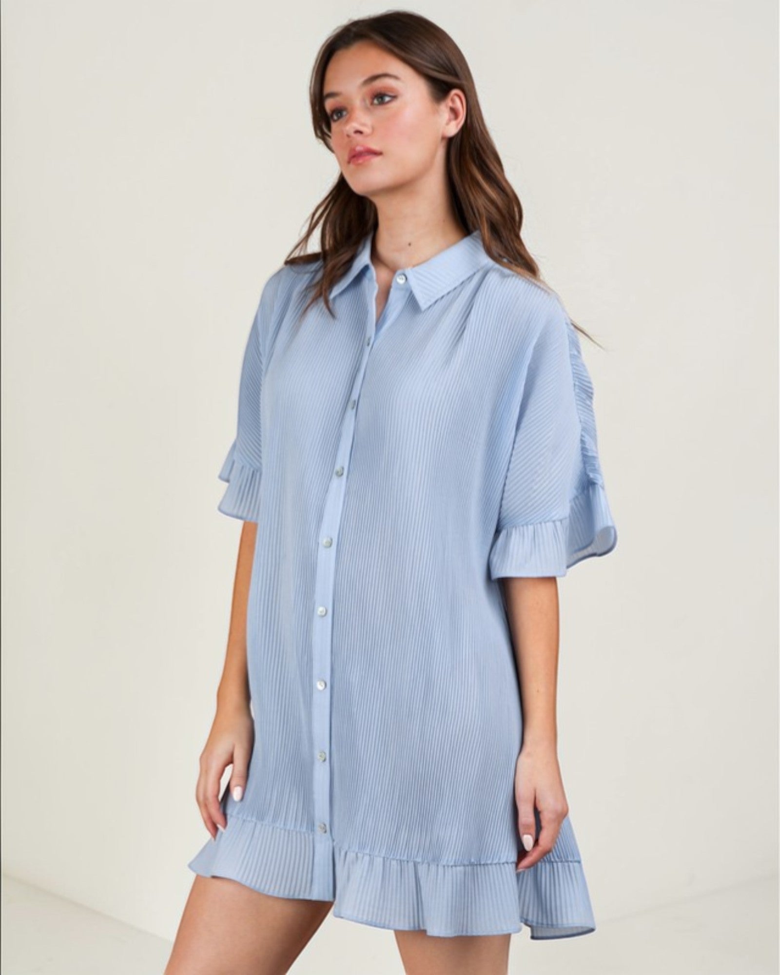 Woman wearing a light blue checkered dress against a plain background