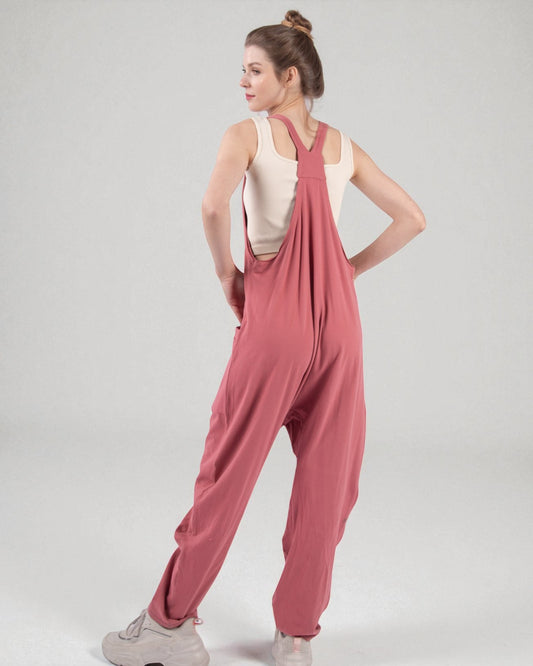 Woman wearing a pink jumpsuit on a plain background