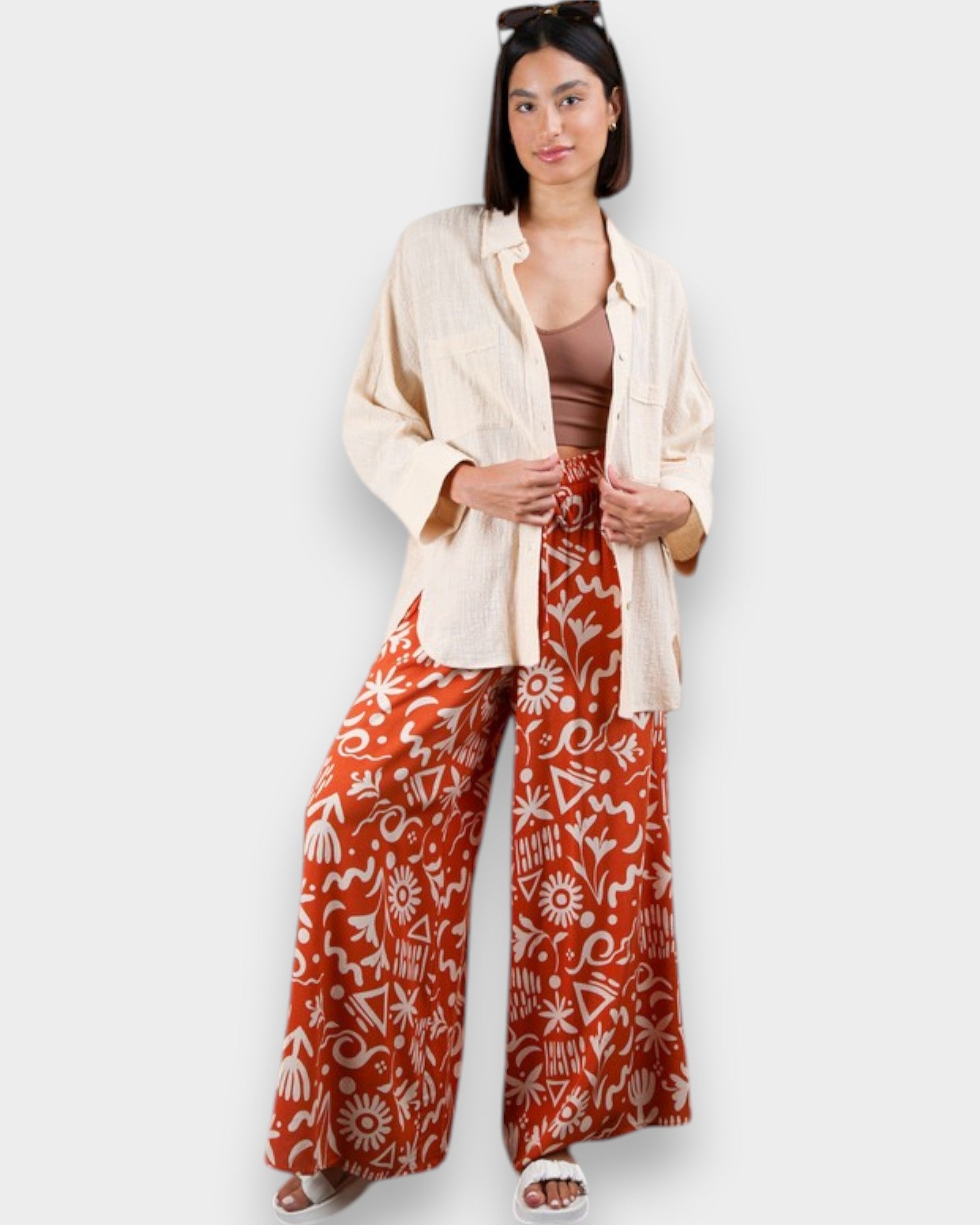 Woman wearing a beige jacket and red patterned pants on a white background