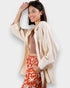 Woman wearing a beige shirt over a brown top and red patterned pants on a white background