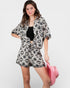 Woman wearing a black and white patterned outfit holding a pink bag on a white background