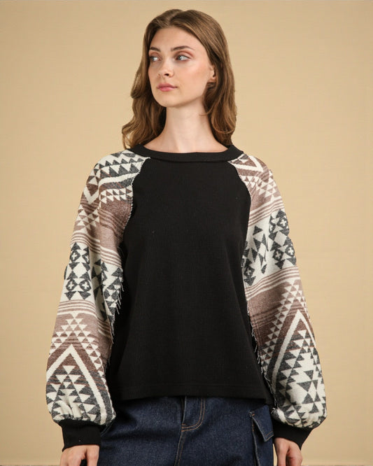 Woman wearing a black shirt with patterned sleeves against a beige background